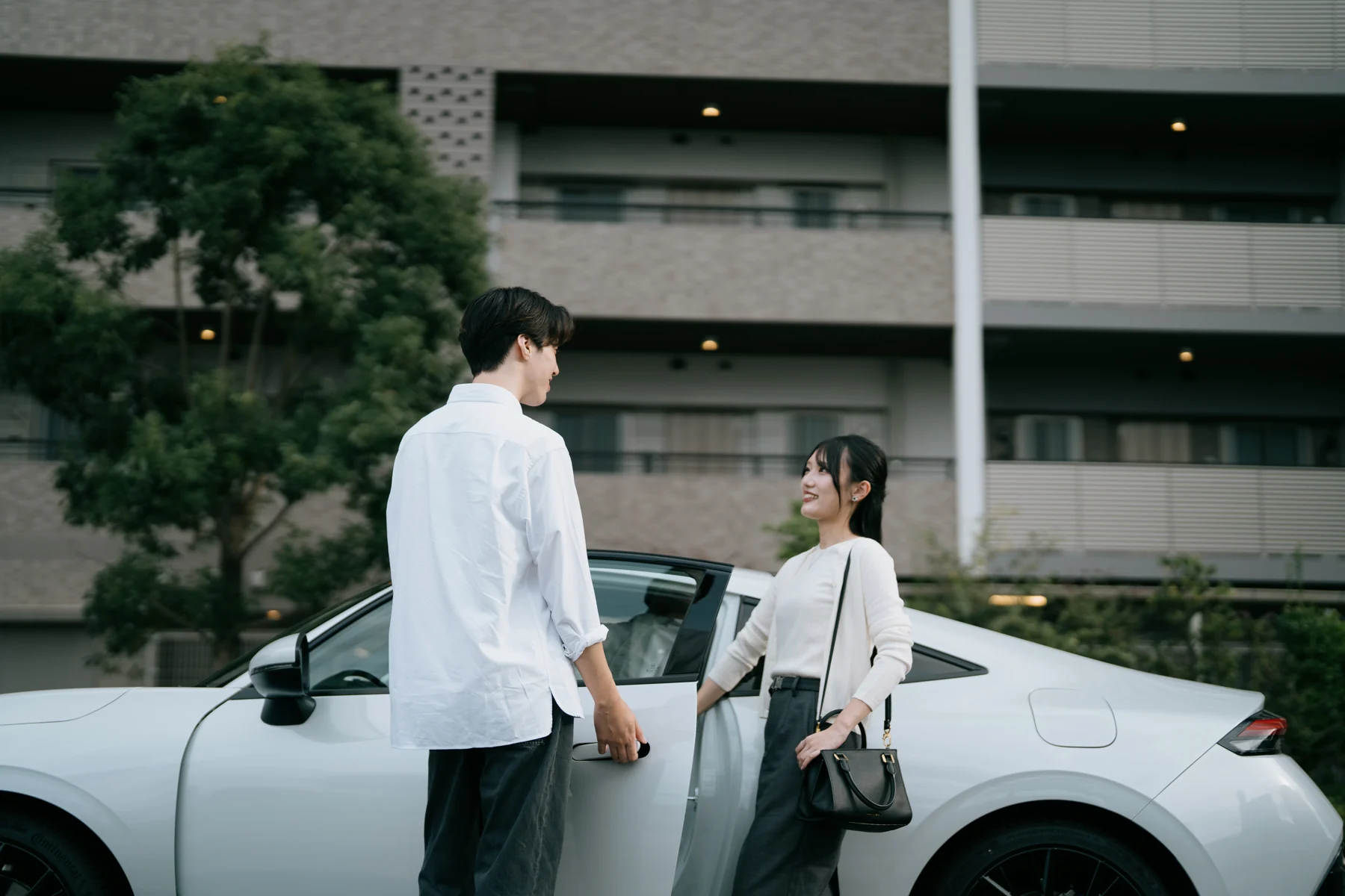 白い車の前で笑顔を交わす二人。Lymoの撮影より